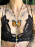 Black lace bra with a butterfly pendant necklace on a tattooed chest.