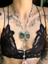 Person wearing a black lace top with a decorative necklace featuring a butterfly pendant.