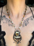 Necklace with butterfly pendant worn by a person with tattoos on their chest.