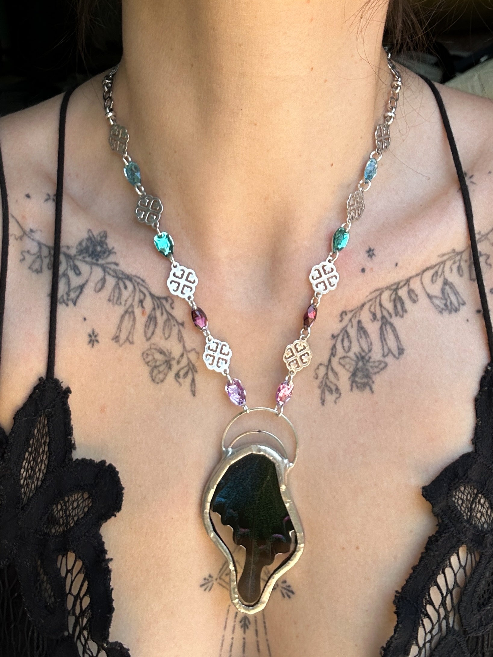 Necklace with a unique butterfly pendant worn by a person with tattoos on their neck.