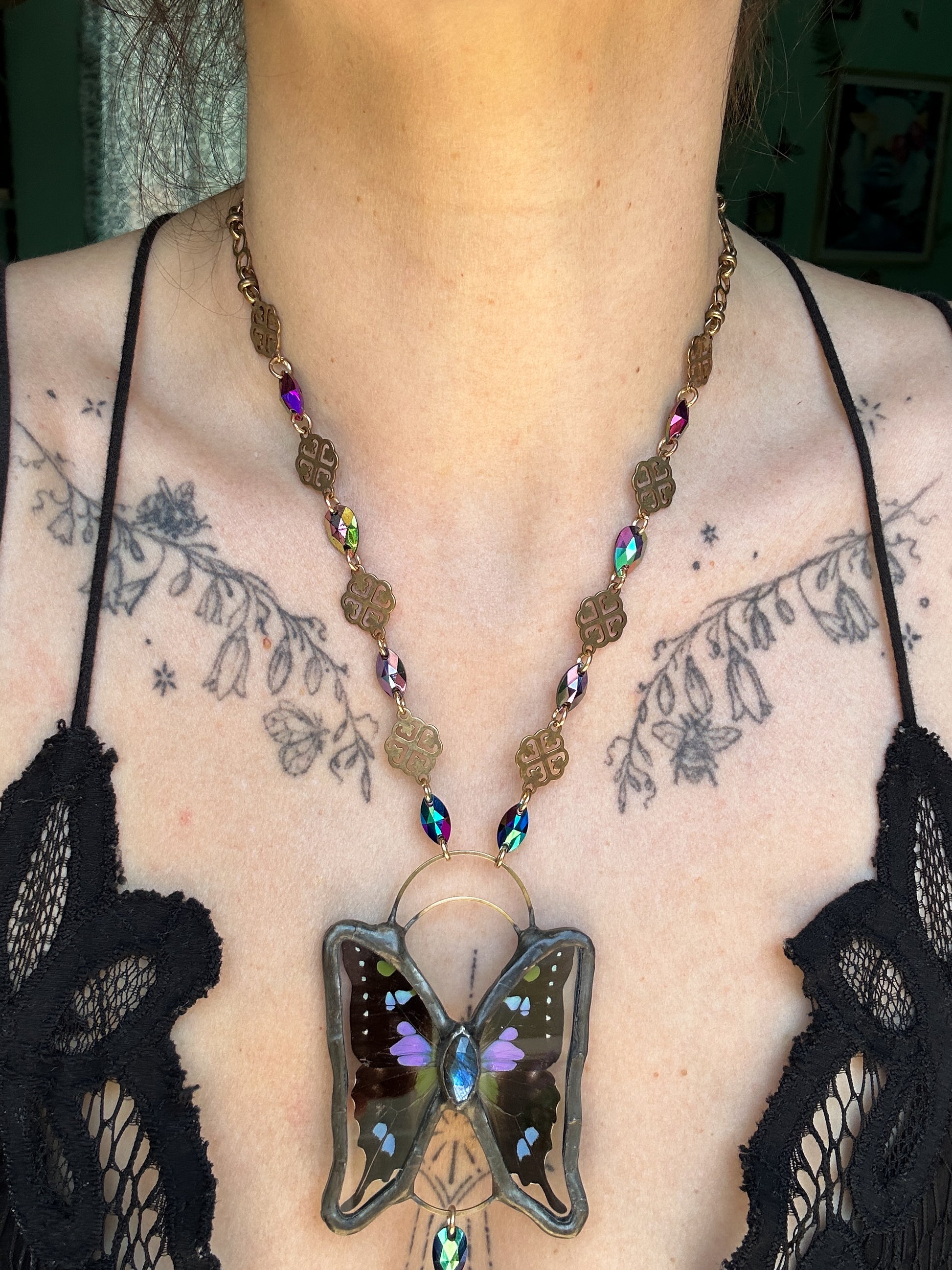Butterfly pendant necklace on a person with tattoos