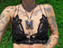 Person wearing a black lace top with a butterfly pendant necklace on a grassy background